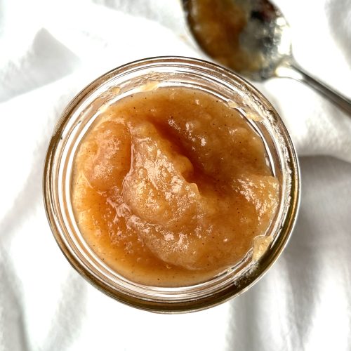 Top view of homemade applesauce in a jar on a white background