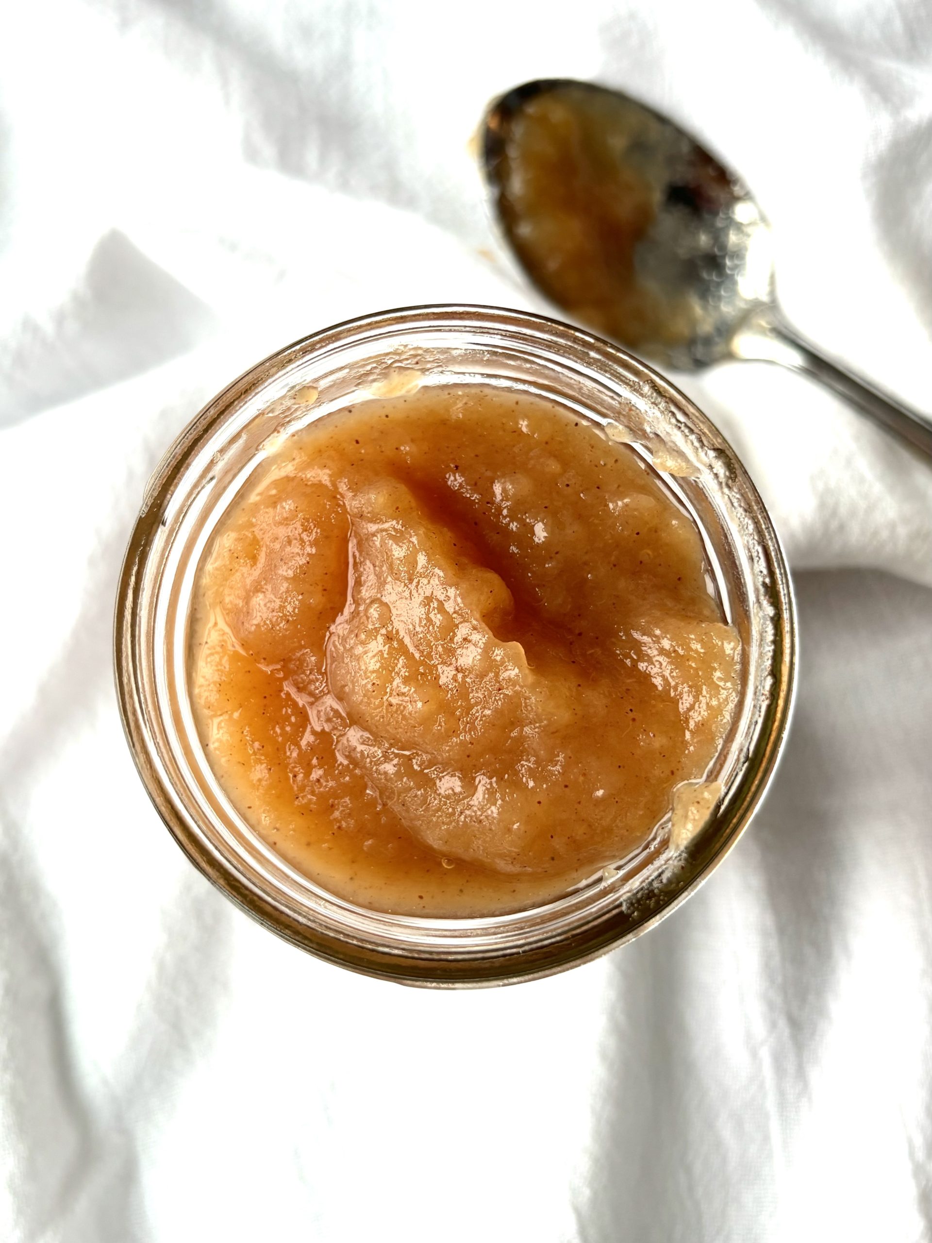 Top view of homemade applesauce in a jar on a white background
