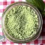 jar of pale green basil garlic salt on a red and white checked tablecloth background