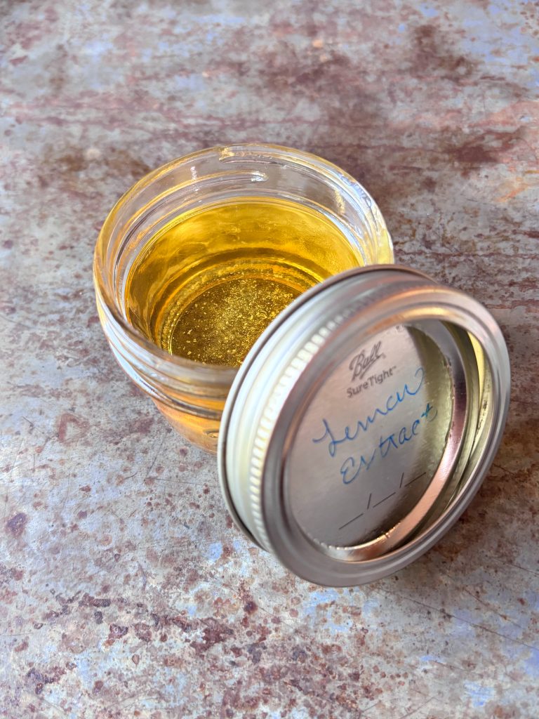 lemon extract in a small mason jar with the lid off and to the side.  Words on lid read "lemon extract"